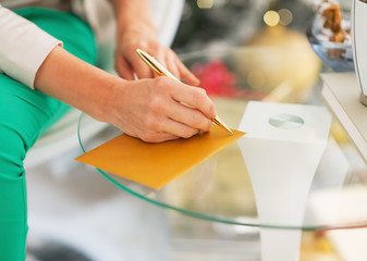 Closeup on woman writing on envelope near christmas tree