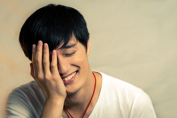 Young man covering his face and smiling