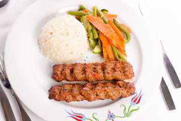 Adana Kebabs Served on a Lavash Bread Garnished with Vegetables