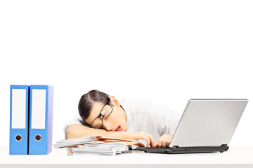 Exhausted young businessman sleeping on a desk at his workplace