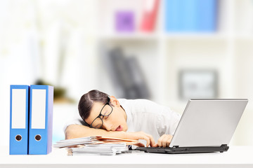 Exhausted businessman sleeping on a desk in his office