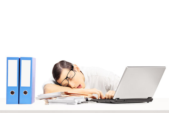 Exhausted young businessman sleeping on a desk at his workplace