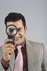 Fototapeta na wymiar Businessman looking through a magnifying glass