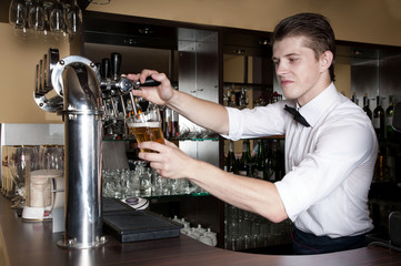 Bartender in white shirt serving beer in front of the bar.