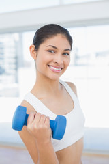 Woman exercising with dumbbell in fitness studio