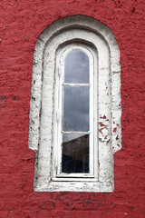 Decorative white window on an old red wall