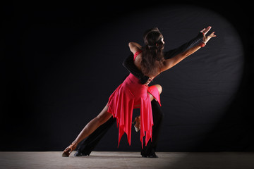 Latino dancers in ballroom against black background