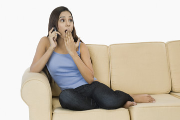 Obraz premium Woman sitting on a couch and talking on a mobile phone