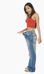Woman pulling jeans from waistline to show weight loss