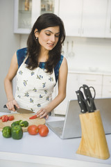 Woman cooking with the recipe on a laptop