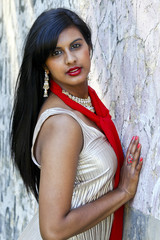 Fototapeta premium Pretty woman leaning against a wall wearing a gold dress