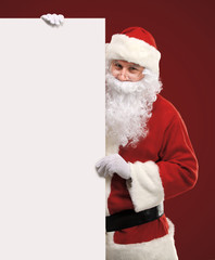 Santa Claus looking out from behind the blank sign isolated
