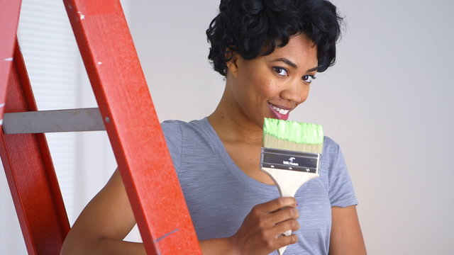 Playful African American woman with paint brush in hand