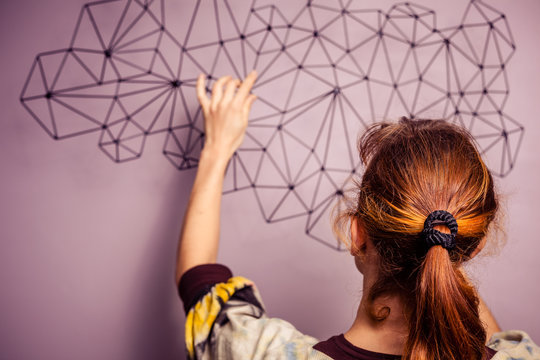 Young woman hanging a piece of art on her wall