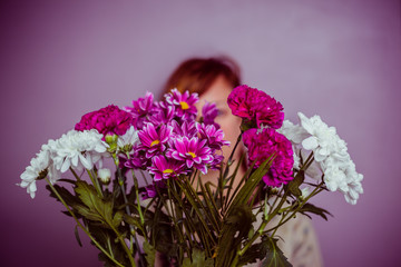 Young woman hiding behind a bouquet of flowers