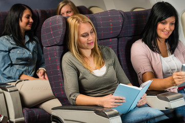 Young woman passenger read book airplane flight