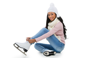 Smiling  woman wearing skates while sitting on the floor.