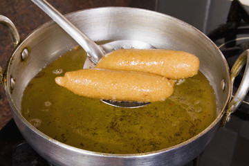 Close-up of pakoras being fried in a pan on a stove