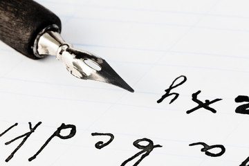 set of letters and black ink nib of drawing pen