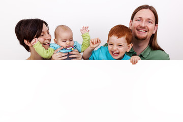 Parents with baby and child behind white wall