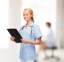 smiling female doctor or nurse with clipboard