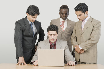Fototapeta na wymiar Three businessmen looking at their colleague using a laptop