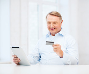 old man with tablet pc and credit card at home