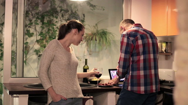 Couple with modern tablet computer drink wine in the kitchen