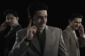 Three businessmen talking on mobile phones