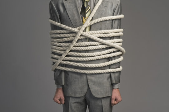 Mid section view of a businessman tied up with ropes
