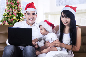 Happy family in santa hats with laptop