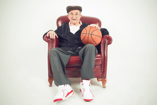 Nice grandfather sitting in a chair holding a basket ball 