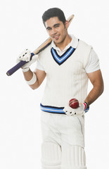 Portrait of a cricket batsman holding a bat and a ball