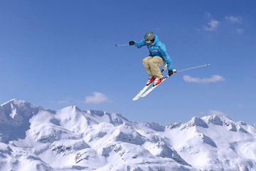 Jumping skier at jump inhigh mountains at sunny day