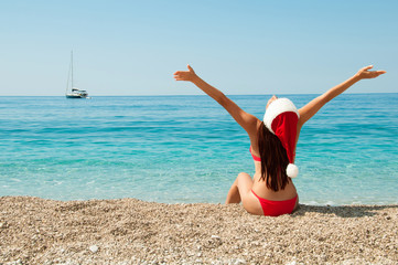 Girl on the beach in a Christmas hat.