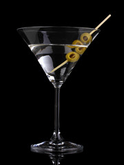 Martini glass and olives isolated on black