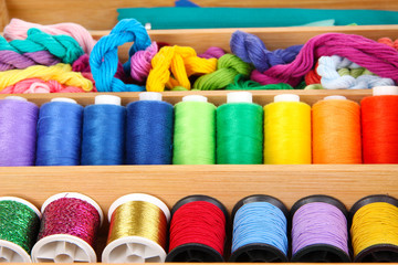 Colorful threads for needlework in wooden box close up