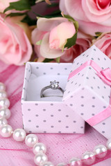 Rose and engagement ring on pink cloth