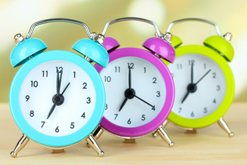 Colorful alarm clocks on table on light background