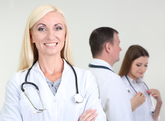 Fototapeta premium Doctor standing in front of coworkers on grey background