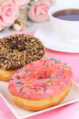 Sweet donuts with cup of tea on table close-up