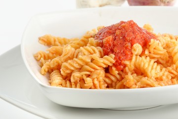Piatto di pasta fusilli al pomodoro su sfondo bianco