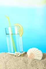 Beach cocktail in sand on blue background