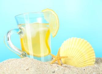 Fototapeta na wymiar Cold tea in sand on blue background