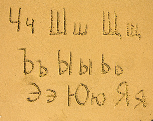 Russian alphabet (from Ch to Ja) written on a sand beach.