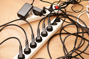 Overloaded power boards, on wooden floor background