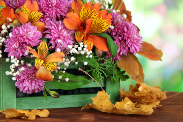 Flowers composition in crate with yellow leaves