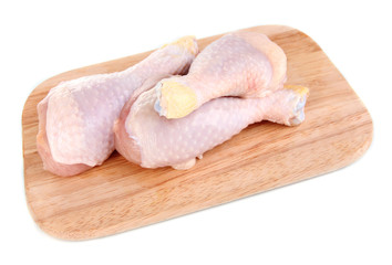 Raw chicken legs on wooden board isolated on white