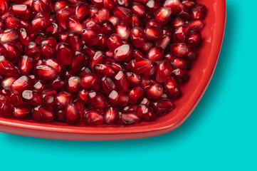 Pomegranate seeds on red heart shaped dish studio shot