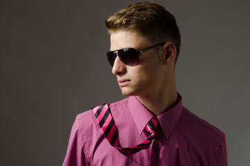 Fototapeta premium Handsome young man with sunglasses wearing a pink shirt